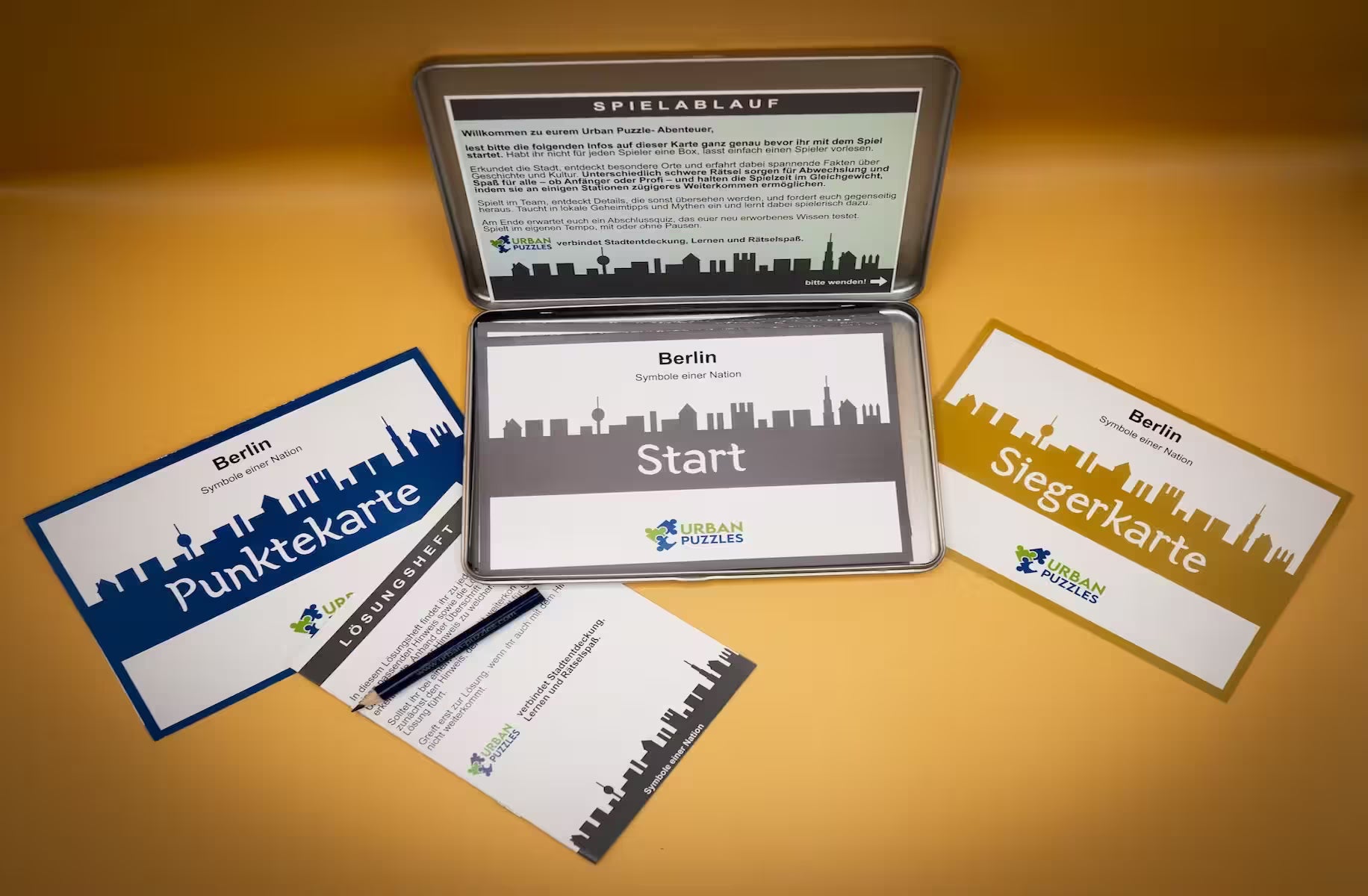 Stadtspiel Berlin Box – Urban Puzzle Spielkarten, Startkarte und Anleitung auf goldenem Hintergrund