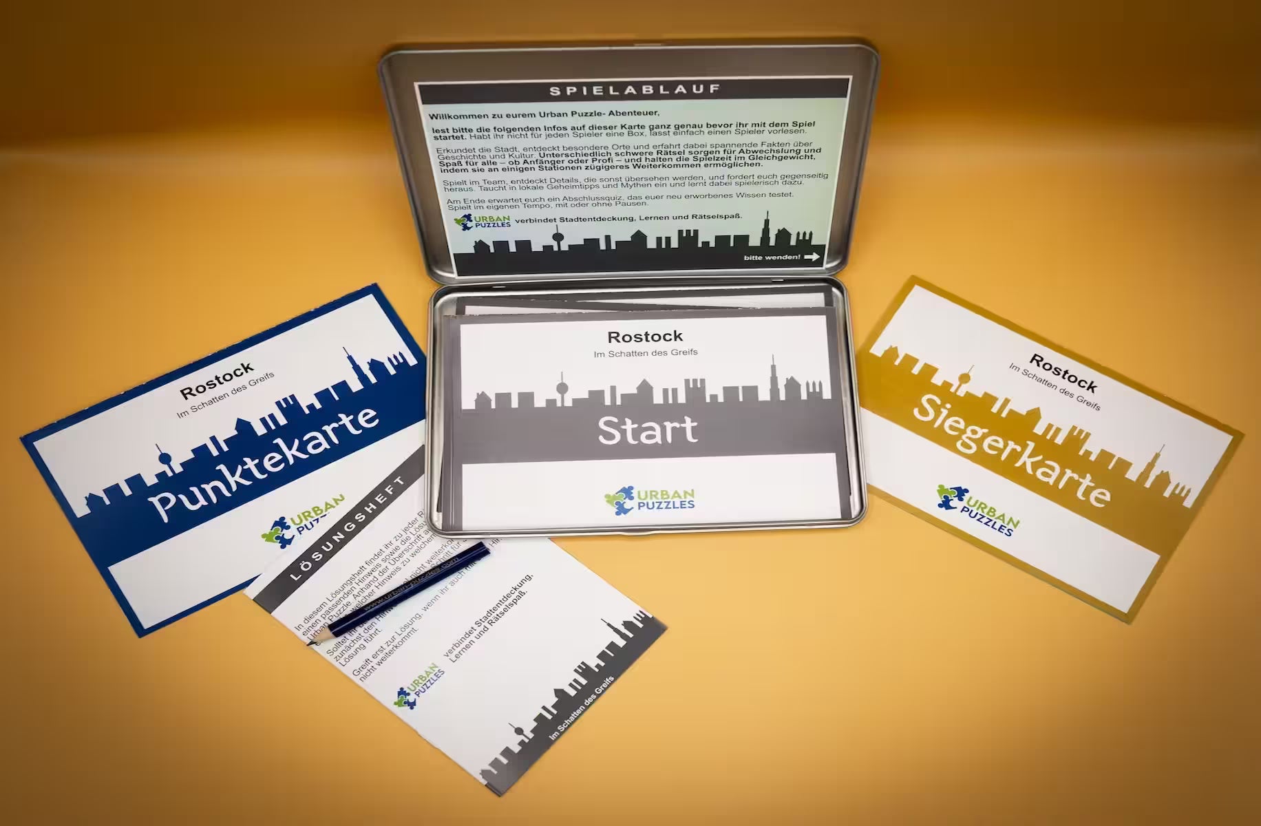Stadtspiel Rostock Box – Urban Puzzle Spielkarten, Punktetafel und Anleitung auf goldenem Grund